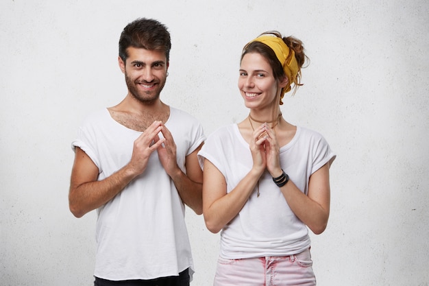 Foto grátis jovem casal astuto e astuto sorrindo misteriosamente, apertando as mãos, tramando ou planejando algo