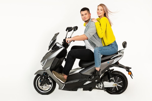 Jovem casal atraente andando de scooter de moto elétrica feliz se divertindo juntos