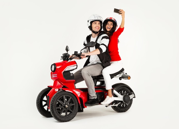 Jovem casal atraente andando de scooter de moto elétrica feliz se divertindo juntos