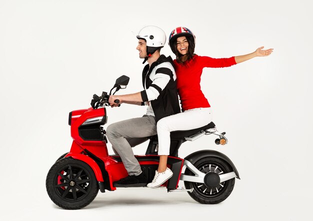 Jovem casal atraente andando de scooter de moto elétrica feliz se divertindo juntos