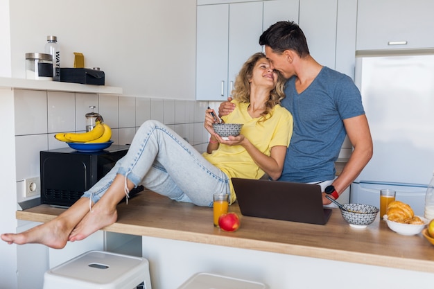 Jovem casal atraente de um homem e uma mulher tomando café da manhã juntos pela manhã na cozinha