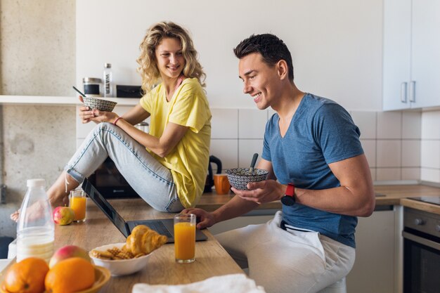 Jovem casal atraente de um homem e uma mulher tomando café da manhã juntos pela manhã na cozinha