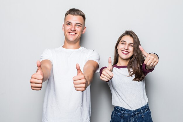 Jovem casal bonito, menino e menina, mostrando sinal de positivo isolado no branco