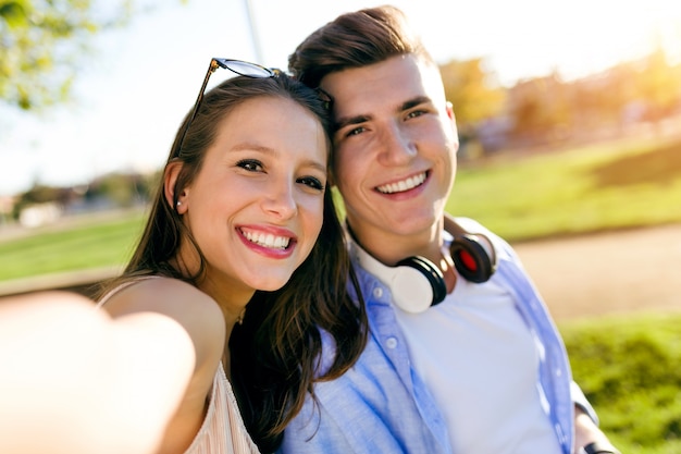 Jovem casal bonito que leva um selfie no parque.