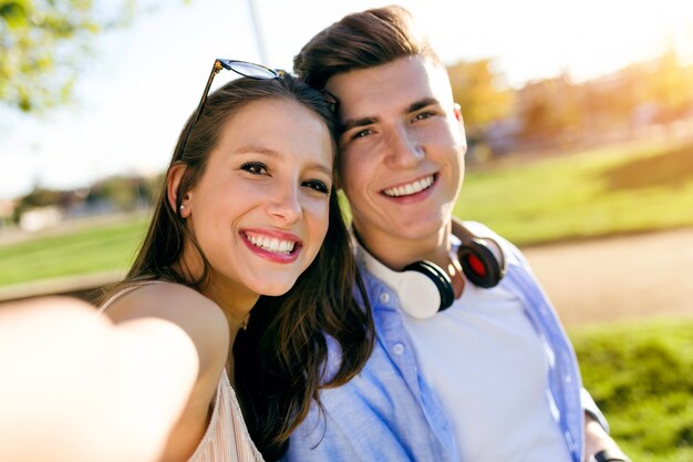 Jovem casal bonito que leva um selfie no parque.