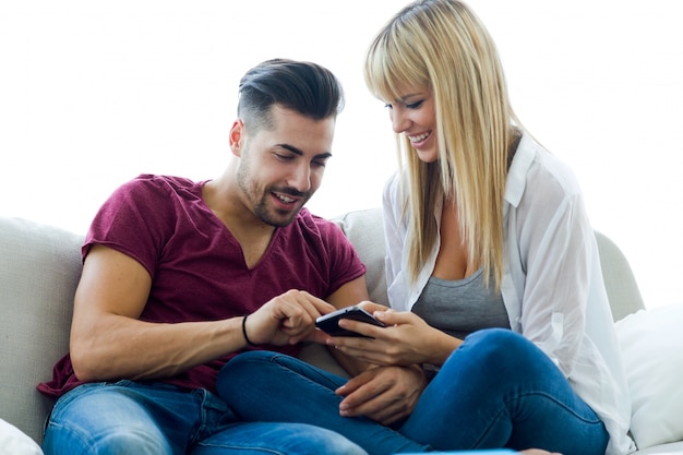 Foto grátis jovem casal bonito usando o telefone móvel em casa.