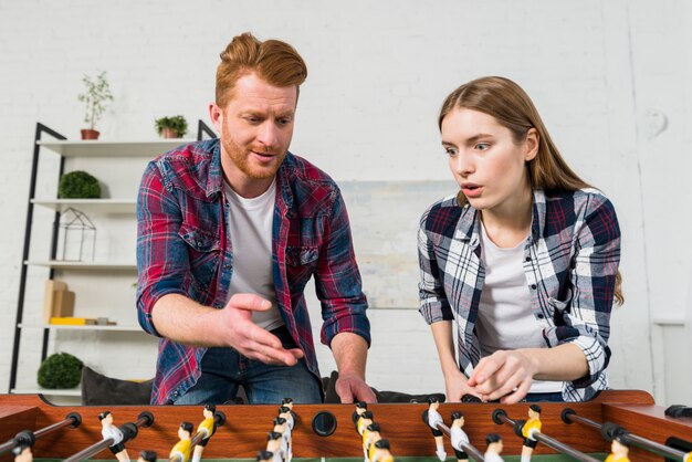 Jovem casal brigando enquanto joga o jogo de futebol de mesa