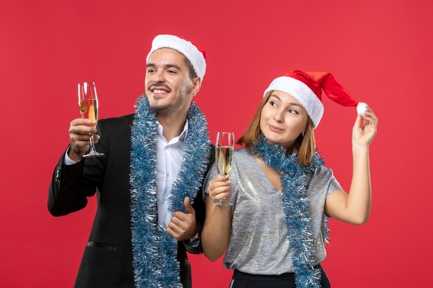 Jovem casal celebrando o ano novo na parede vermelha de frente