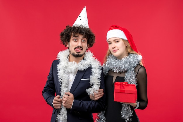 Jovem casal com ano novo presente na parede vermelha festa de amor de natal