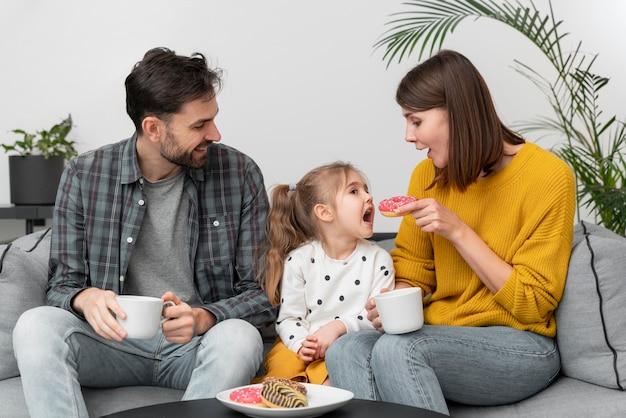 Jovem casal com criança comendo donuts