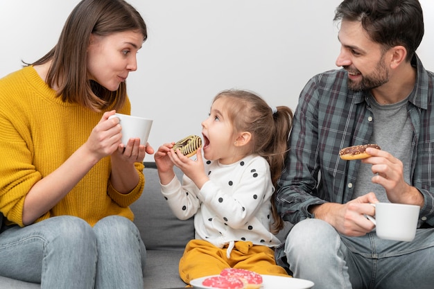 Jovem casal com criança comendo donuts