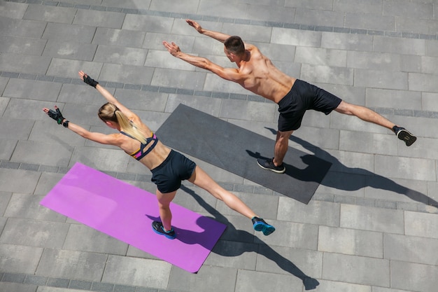 Jovem casal com roupa esportiva, fazendo exercícios matinais ao ar livre.