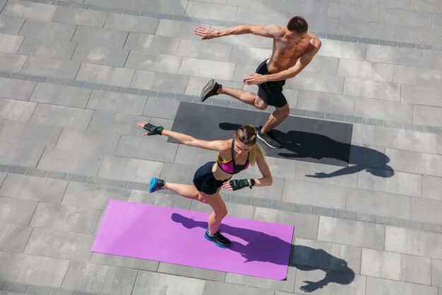 Jovem casal com roupa esportiva, fazendo exercícios matinais ao ar livre.