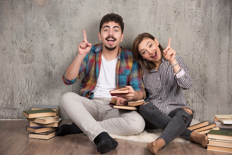 Foto grátis jovem casal com um livro interessante apontando para cima