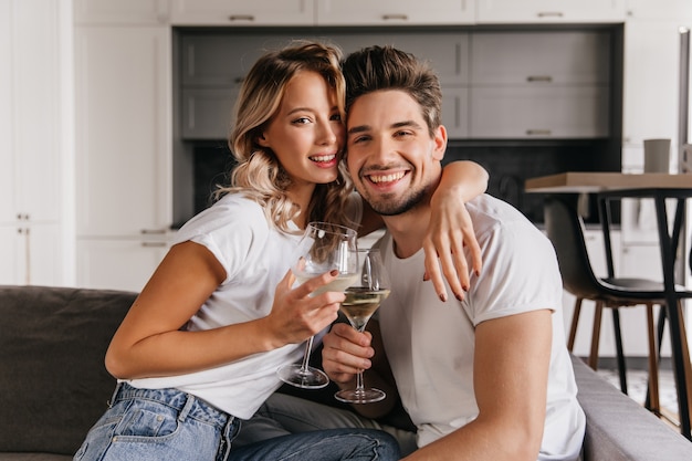 Jovem casal comemorando aniversário em casa. mulher satisfeita bebendo champanhe com o marido.