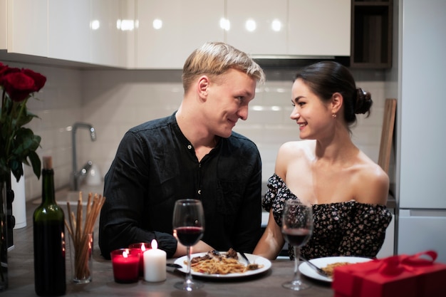 Jovem casal comemorando o dia dos namorados enquanto almoçam e tomam vinho juntos