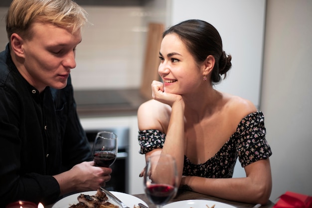Jovem casal comemorando o dia dos namorados enquanto almoçam e tomam vinho juntos