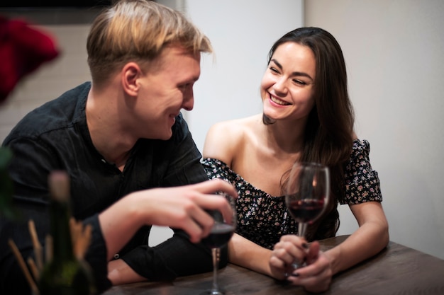 Jovem casal comemorando o dia dos namorados enquanto almoçam e tomam vinho juntos