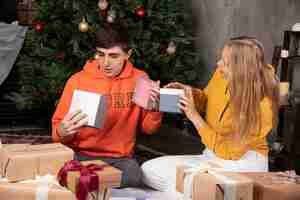 Foto grátis jovem casal comemorando o natal em casa com presentes.