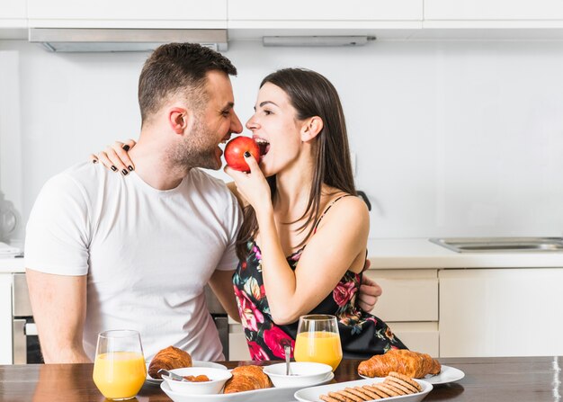 Jovem casal comendo maçã com café da manhã na mesa de madeira