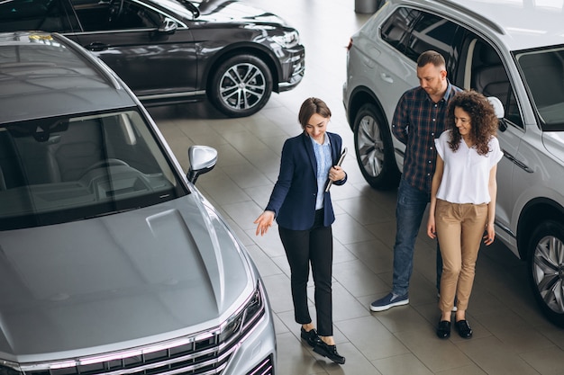 Jovem casal conversando com uma pessoa de vendas em um showroom de carros