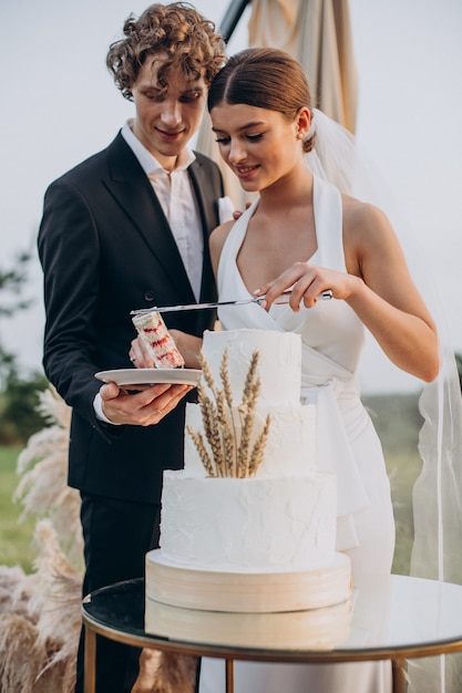 Jovem casal cortando bolo de casamento