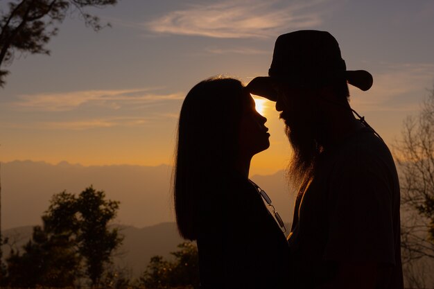 Jovem casal curtindo o pôr do sol na montanha