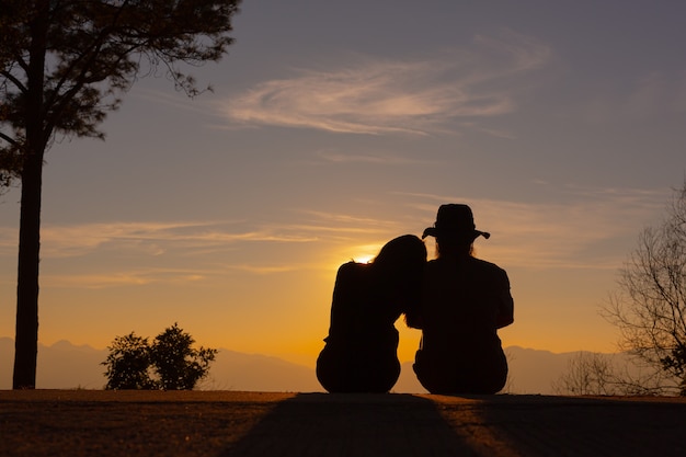 Jovem casal curtindo o pôr do sol na montanha