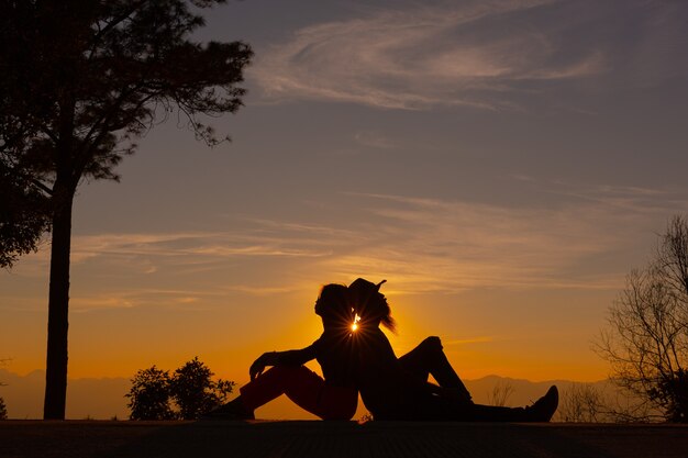 Jovem casal curtindo o pôr do sol na montanha