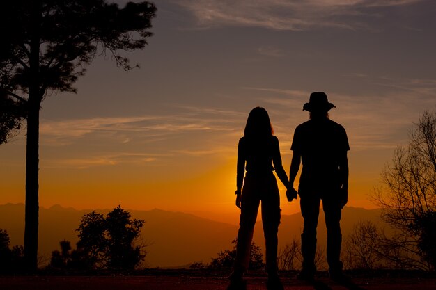 Jovem casal curtindo o pôr do sol na montanha