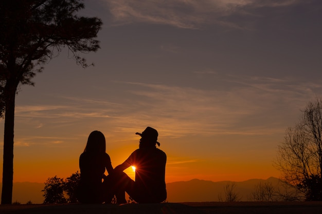 Jovem casal curtindo o pôr do sol na montanha