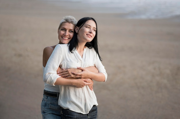 Jovem casal de lésbicas se abraçando à beira-mar