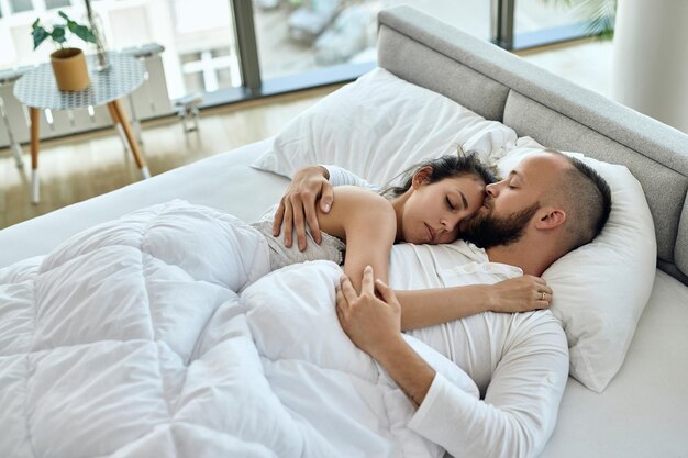 Jovem casal desfrutando enquanto dorme abraçado no quarto