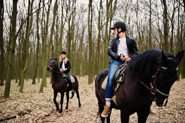 Jovem casal elegante, andar a cavalo na floresta de outono