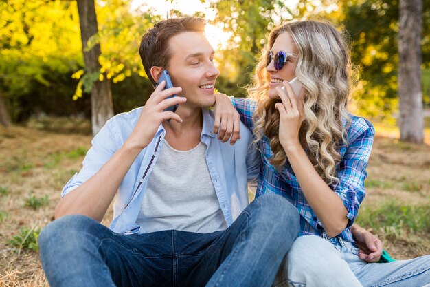 Jovem casal elegante sentado no parque, sorrindo, homem e mulher, família feliz juntos, conversando ao telefone