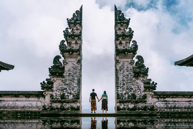 Jovem casal em pé nos portões do templo e de mãos dadas no templo Lempuyang Luhur em Bali, Indonésia. Tom vintage