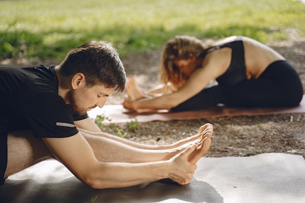 Jovem casal esportivo fazendo ioga fitness. pessoas em um parque de verão.