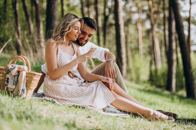 Jovem casal fazendo piquenique na floresta