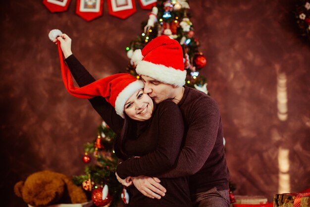 Jovem casal feliz abraçando perto da árvore de Natal