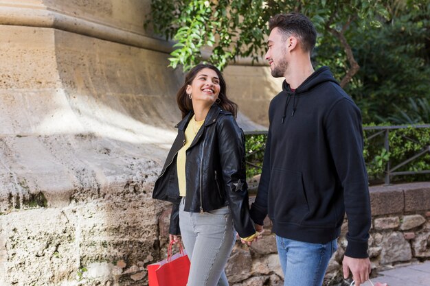 Jovem casal feliz andando na rua perto de plantas