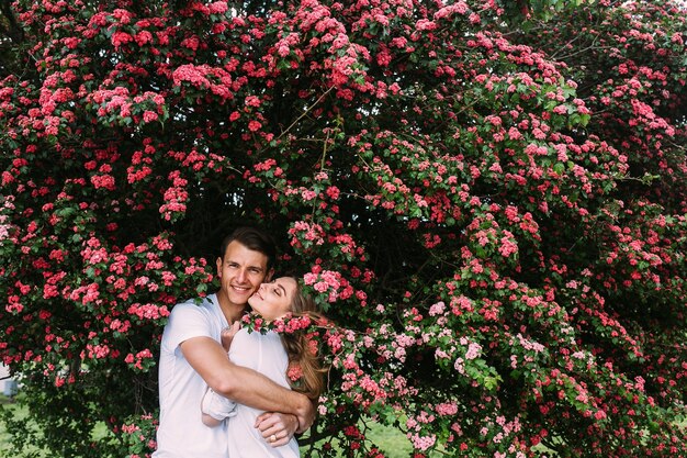 Jovem casal feliz apaixonado ao ar livre. amar o homem e a mulher em uma caminhada em um parque florido de primavera