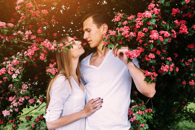 Jovem casal feliz apaixonado ao ar livre. amar o homem e a mulher em uma caminhada em um parque florido de primavera