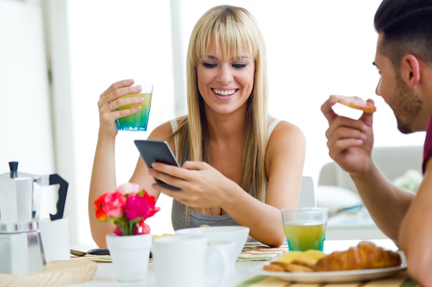 Jovem casal feliz desfrutando de café da manhã na cozinha.