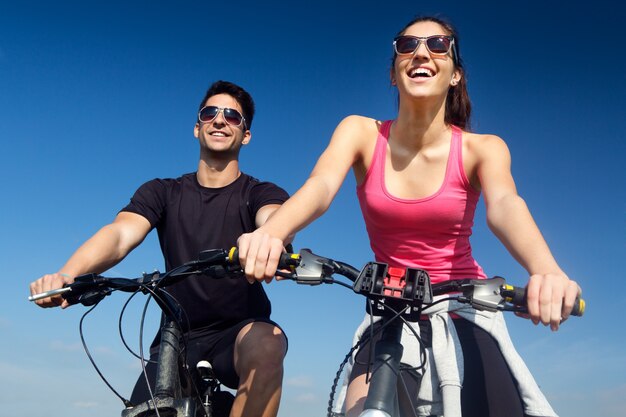 Jovem casal feliz em um passeio de bicicleta no campo