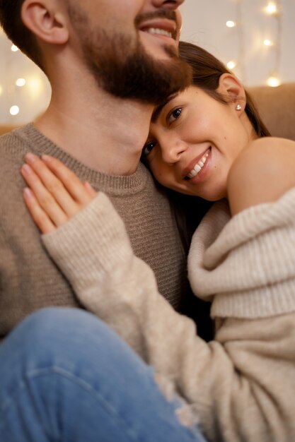 Jovem casal feliz se abraçando, sentados no sofá aconchegante juntos
