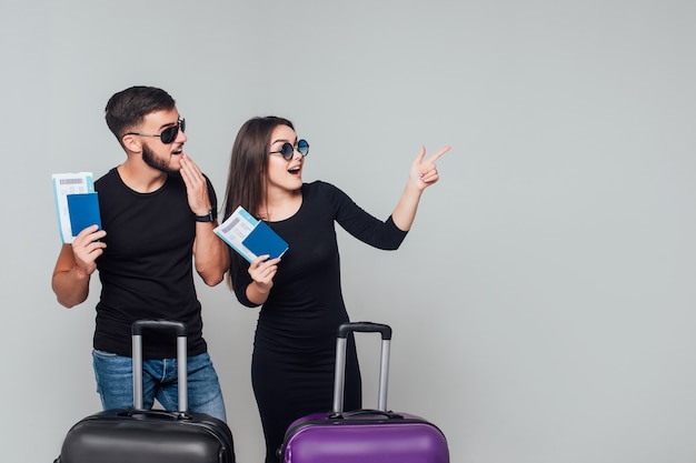 Jovem casal feliz sorridente com malas e passagens isoladas em branco