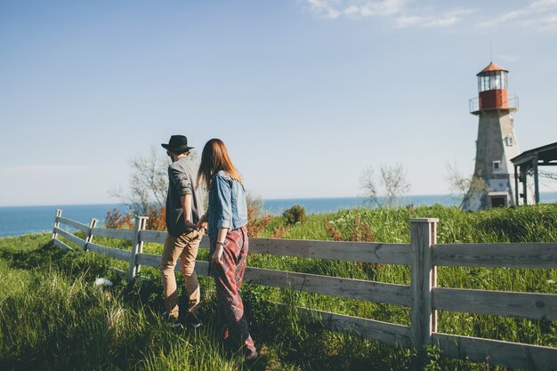 Jovem casal hippie estilo indie apaixonado caminhando pelo campo