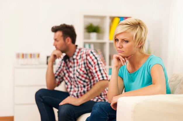 Jovem casal infeliz sentado na sala de estar