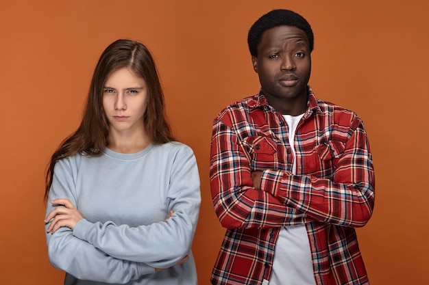 Jovem casal interracial irritado, esposa e marido, cruzando os braços e carrancudo discutindo, brigando pela reforma em sua casa. conceito de problemas de relacionamento e pessoas