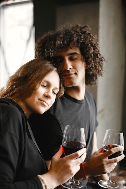 Jovem casal juntos segurando taças de vinho.